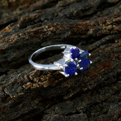Noelia blue trilogy ring for women with three deep blue gemstones set in silver band on textured wood