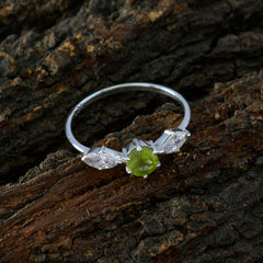 Hana modern green gemstone ring with silver band and side clear stones on wood background