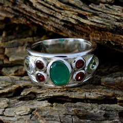 Natcha multicolor gemstone ring with green and red stones set in silver band on textured wood
