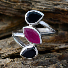 Priya multicolor gemstone trilogy ring with black and pink stones set in silver band on rustic wood