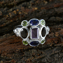 Meera navratna cocktail ring with multicolored gemstones set in silver on a rustic background