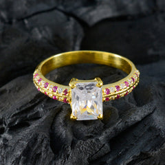 Camila gold ring featuring a central clear gemstone with a band decorated by small romantic red gemstone ring accents