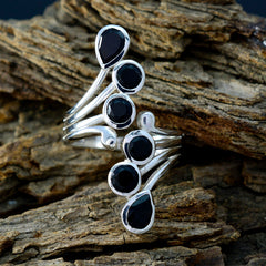 Violet black gemstone ring with multiple black stones set in silver bands displayed on rustic wood