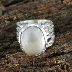 Ella white solitaire statement ring with a large oval white stone on a textured natural background