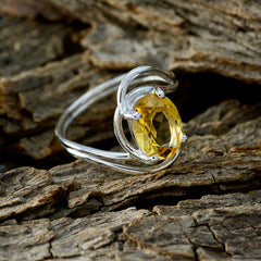 Saanvi yellow solitaire ring with oval yellow gemstone set in silver band on textured wood