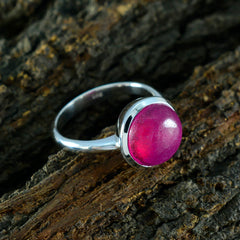 Lakshmi red solitaire ring with round red gemstone set in silver band on rustic wood