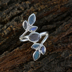 Anna leaf design gemstone ring with blue and gray stones on a silver band placed on tree bark