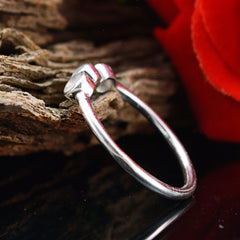 Yuki silver band showcasing light green gemstone trilogy ring style setting beside red rose and driftwood