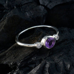 Naomi luxury purple gemstone ring with silver band and two small clear stones on black textured background
