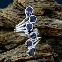 Yasmine modern blue gemstone ring with multiple blue stones set in silver band on rustic wood