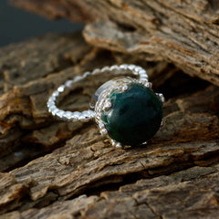 Riya modern green solitaire ring with twisted silver band and round green stone on rustic wood