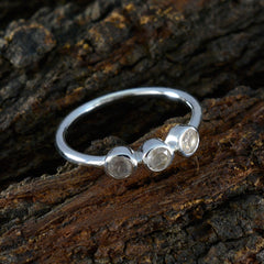 Saanvi modern pink trilogy ring with three clear stones set in a silver band on rustic wood