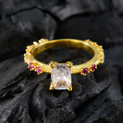 Liyana gold ring with emerald cut clear center stone and small ruby accents on band modern red gemstone ring