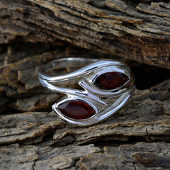 Milagros modern toi et moi ring with two marquise red gemstones set in silver band on textured wood