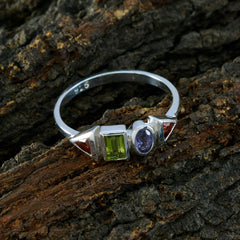 Mei silver multicolor gemstone ring with green, purple, and red gemstones on textured bark