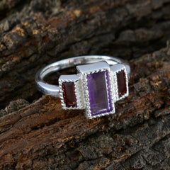 Constanza multicolor gemstone trilogy ring with purple and red stones set in silver band on wood background