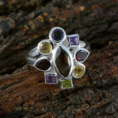 Araya multicolor navratna ring with various gemstone cuts on silver band on rustic wood