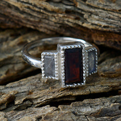 Silver Eleanor multicolor trilogy ring with rectangular dark red center stone and two gray side stones on wood