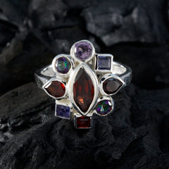 Angel navratna gemstone ring with multicolored gemstones set in silver band displayed on dark textured background