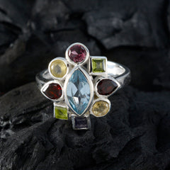 Paula navratna gemstone ring with multicolored stones set in silver band on dark textured background