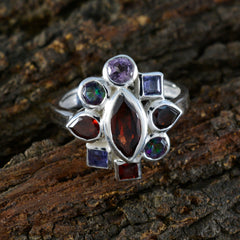 Angel navratna gemstone ring with multi-colored stones set in silver band on textured wood