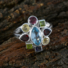 Paula navratna gemstone ring with multicolor stones set in silver band on wooden background