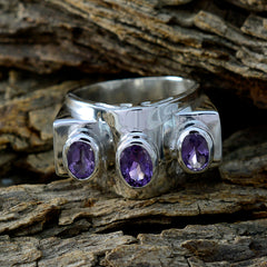 Olivia purple gemstone ring with three oval purple gemstones set in a silver band on rustic wood