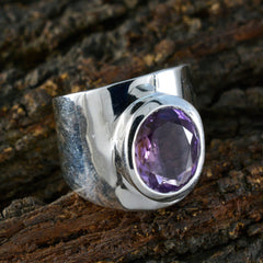 Fernanda silver purple gemstone solitaire ring with a large faceted oval stone on rustic wood background