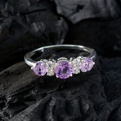 Emi purple gemstone trilogy ring with three purple gemstones and silver band on black textured background