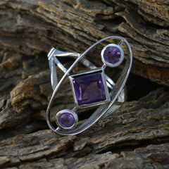 Renata purple gemstone trilogy ring with silver band and three purple gemstones on textured wood