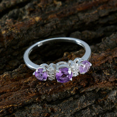 Emi purple gemstone trilogy ring with three purple stones set in silver band on rustic wood