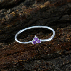 Ling purple gemstone trilogy ring with three small purple stones set on a silver band on rustic wood
