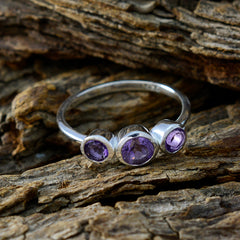 Lily purple gemstone trilogy ring with three round purple stones set in silver band on rustic wood