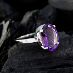 Andrea purple solitaire ring with oval gemstone set on silver band on dark textured background