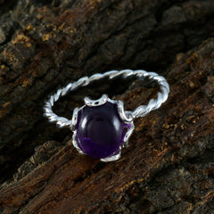 Yan purple solitaire ring with twisted silver band and round purple gemstone on bark background