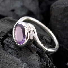 Angel purple solitaire ring with oval gemstone set in sleek silver band on black textured surface