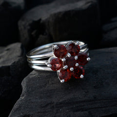 Natalie red floral gemstone ring with six round red stones on silver band on dark textured surface