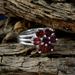 Natalie red floral gemstone ring with silver band displayed on rustic wood background