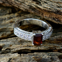 Victoria red gemstone halo ring with rectangular red stone and detailed silver band on rustic wood