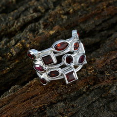 Freya red gemstone statement ring with multiple red stones set in silver band on textured wood