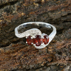 Xiu sterling silver red gemstone trilogy ring featuring three oval red gemstones and pave accents on a twisted band