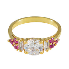 Araya gold ring with clear center stone and red halo gemstone ring accents on each side