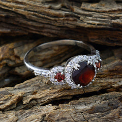 Maria red halo ring for women silver band with central oval red gemstone haloed by diamonds and side stones on wood