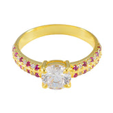 Xiu red halo ring gold with a large central clear stone and small red stones on the gold band