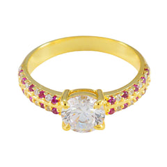 Xiu red halo ring gold with a large central clear stone and small red stones on the gold band