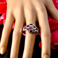 Paula silver ring with red navratna ring design on a mannequin hand with red flowers background