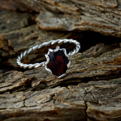 Wen red solitaire gemstone ring with twisted silver band on rustic wood background
