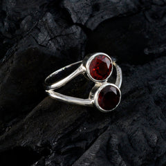 Olivia red toi et moi ring with two round red gemstones set in silver band on dark textured background