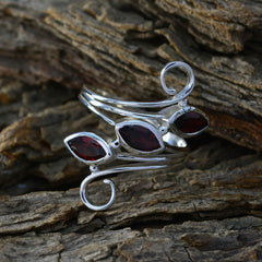 Ayesha silver ring featuring a red trilogy gemstone ring with three marquise-cut red stones on a rustic wood background