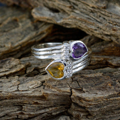 Lucia toi et moi heart ring with purple and yellow heart-shaped gemstones on textured wood background